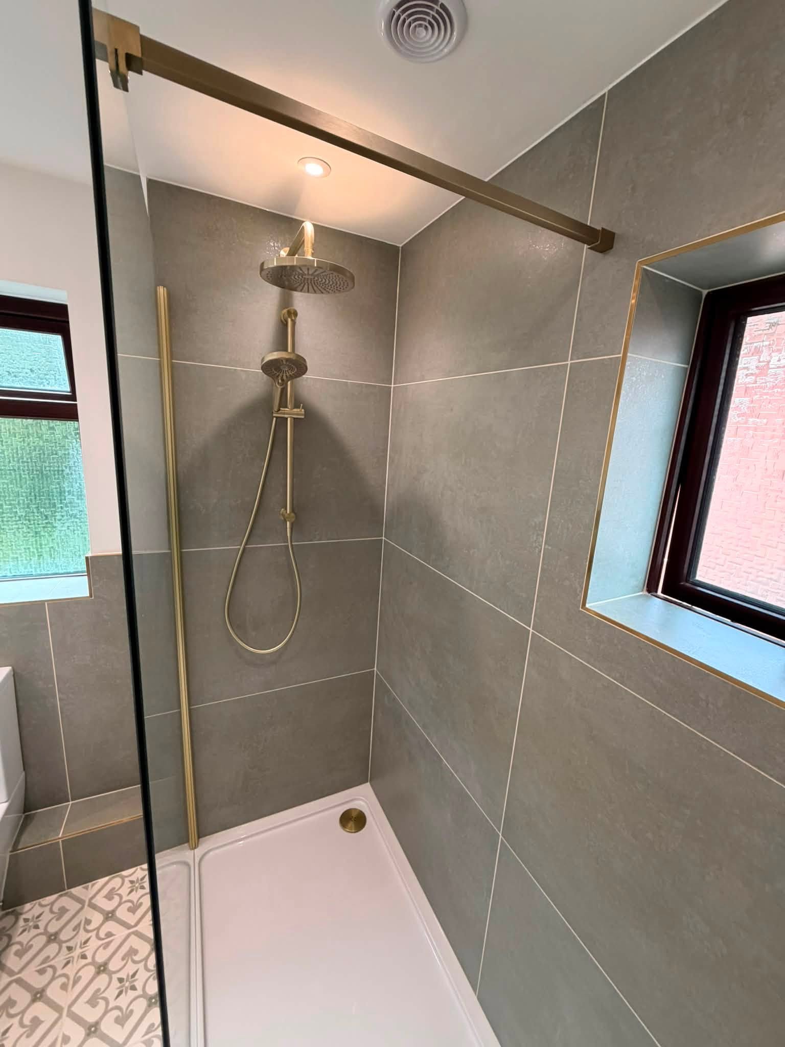 After: walk-in shower with a brushed brass rail and large grey tiles