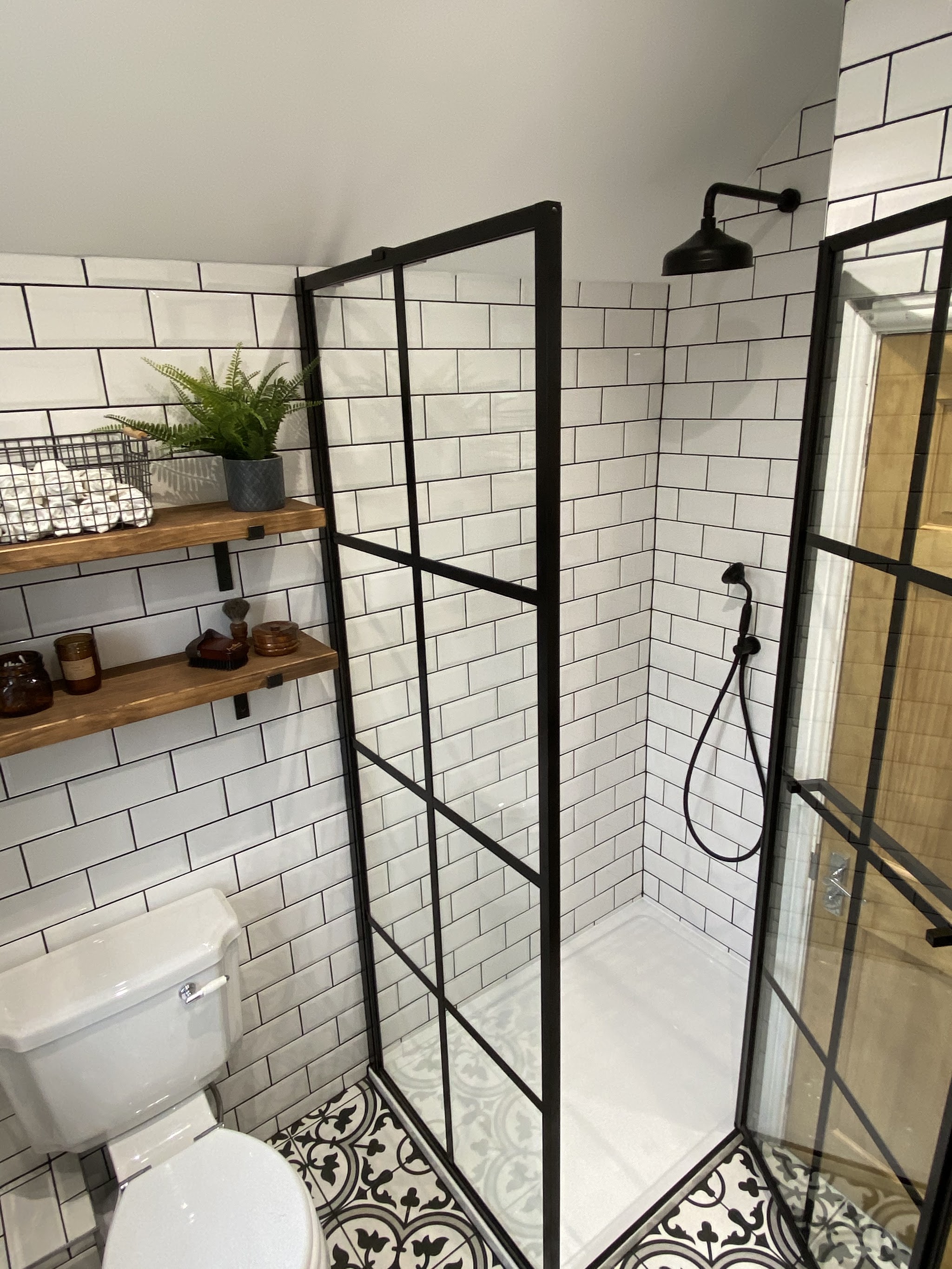 Black grid shower screen, white metro tiles and a patterned floor